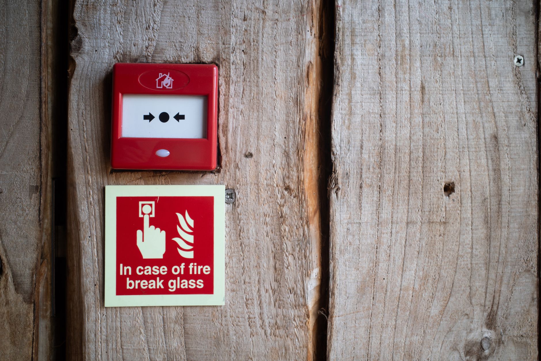 Red fire alarm and warning sign on a rustic wooden wall for safety awareness indoors