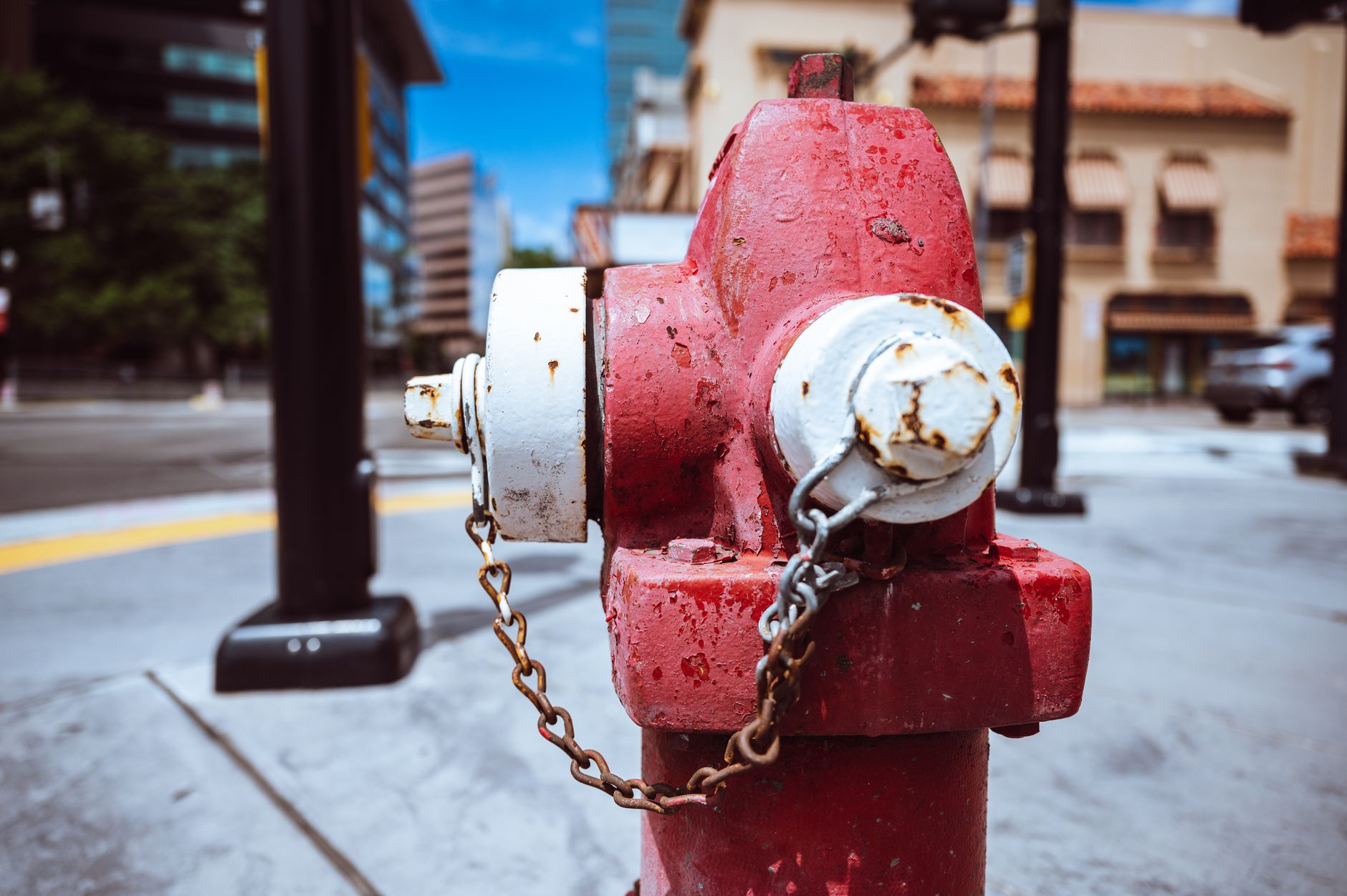 Typical red fire hydrant with rusty chain located on roadside in modern city on sunny day